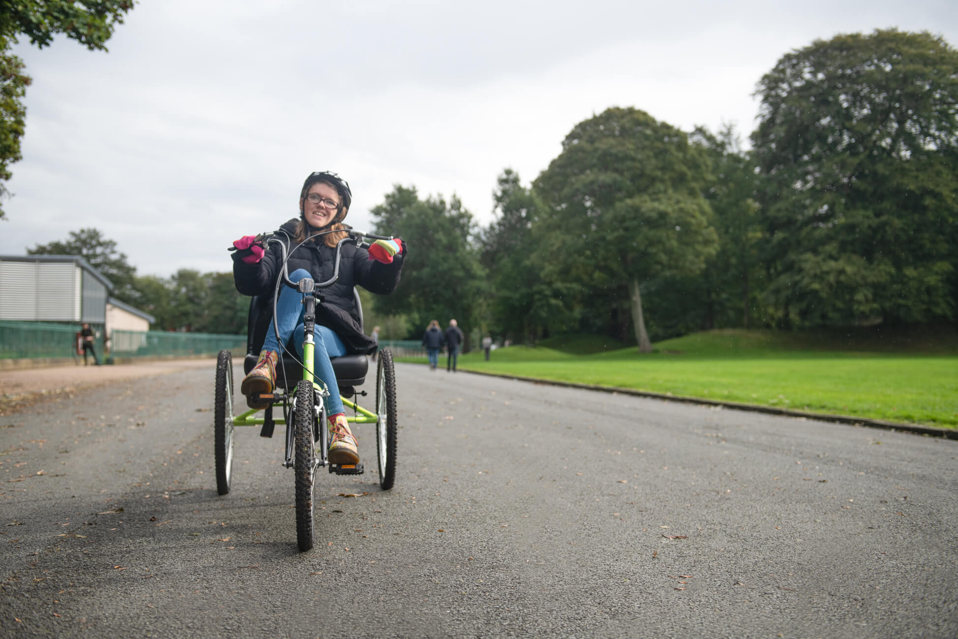 A young woman cycling on a specially adapted cycle in Birkenhead Park