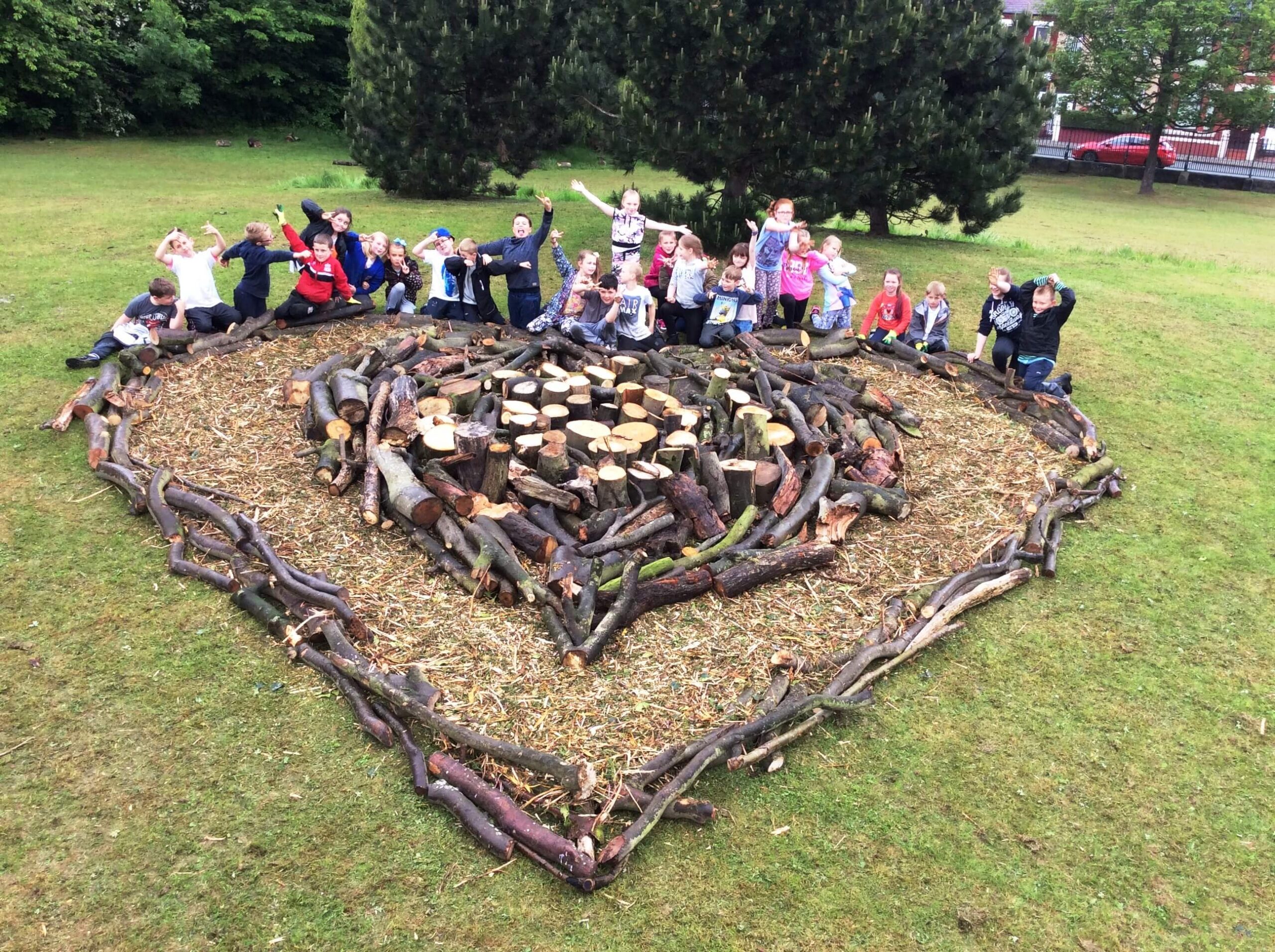 A group of school children posing at the Finnish Heart made from logs
